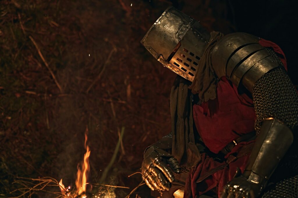 Knight in armor rests by a campfire