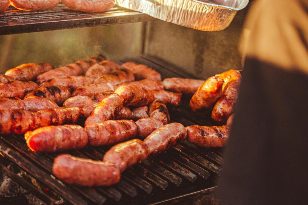 Close-up of flavorful sausages grilling on barbecue, perfect for a summer meal.