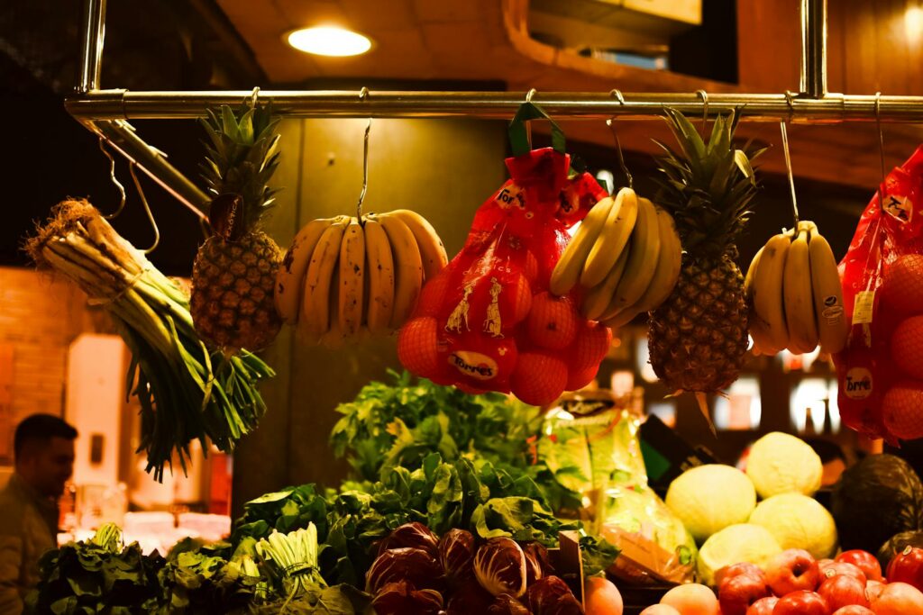 Colorful assortment of fresh fruits and vegetables hanging at an indoor market stall.