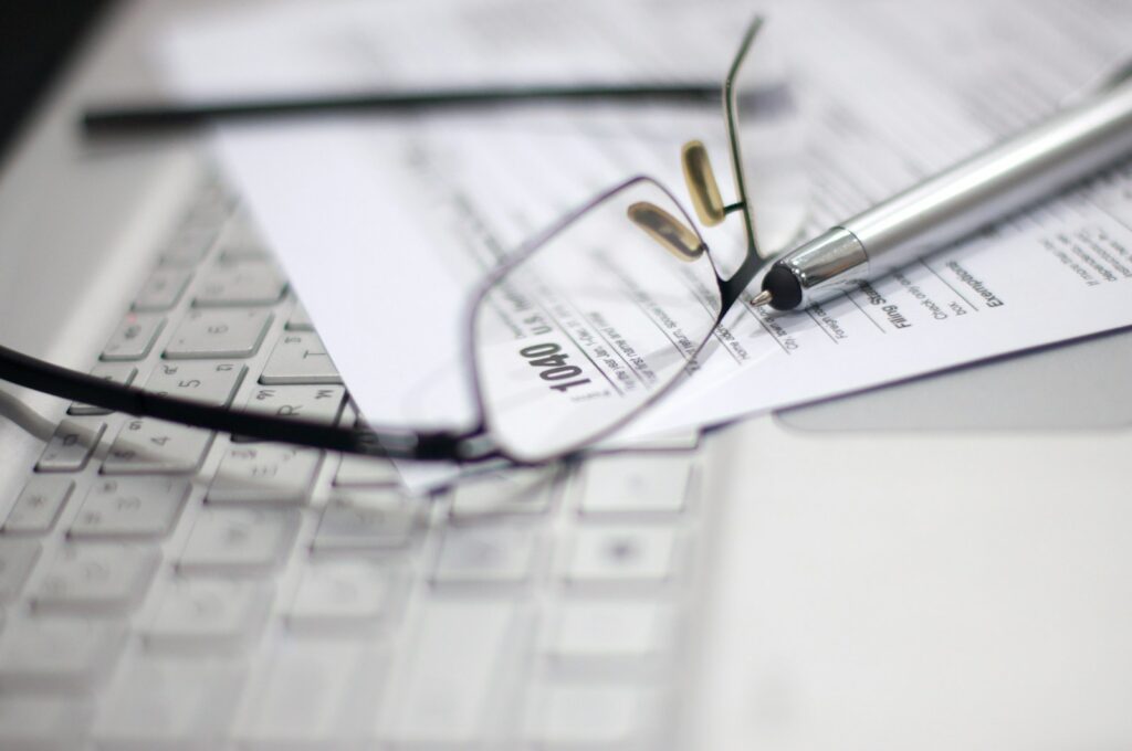 Glasses and pen on tax form and laptop.