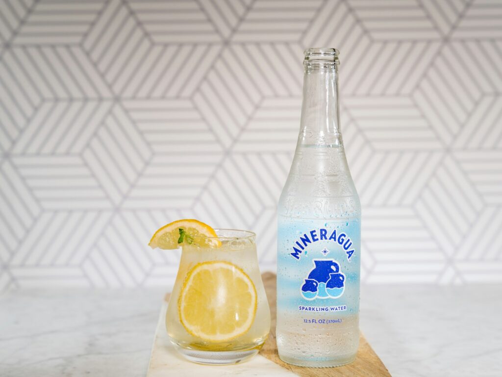 blue and white labeled bottle beside clear drinking glass