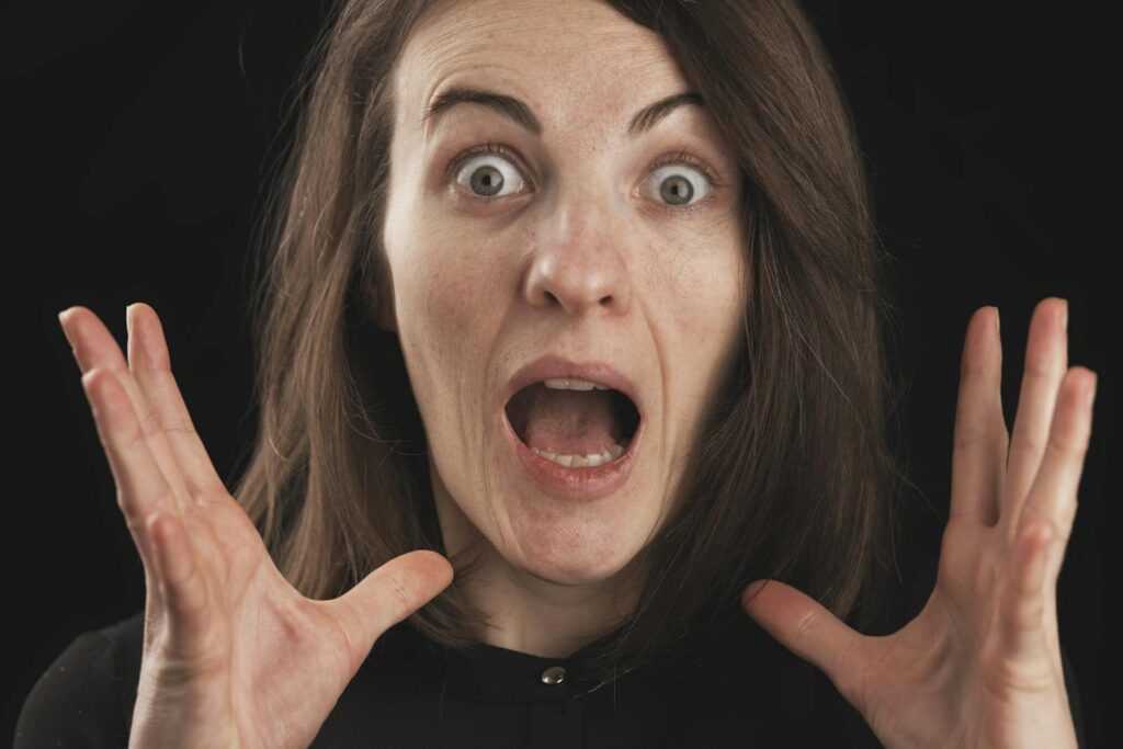 Close-up of a woman expressing shock and surprise with wide eyes and open mouth.