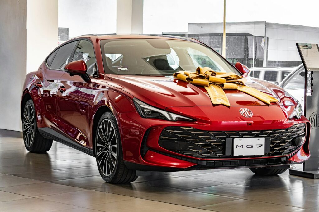Red car with a large gold bow on hood