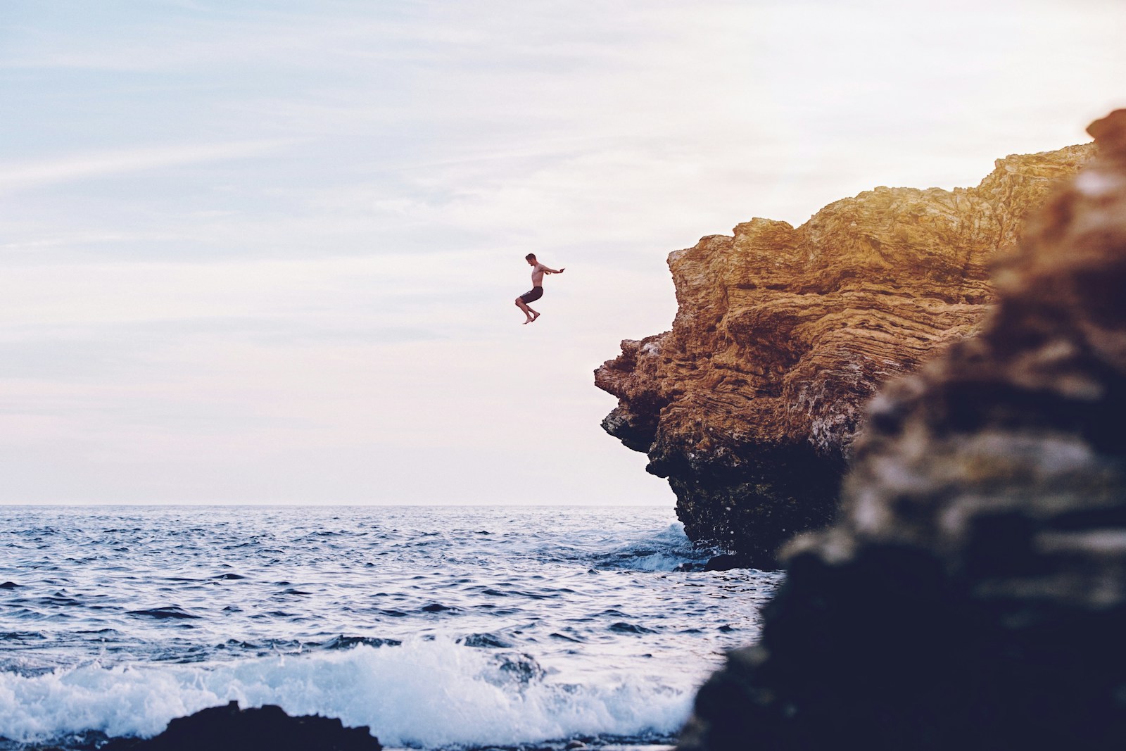 person jumping to body of water during daytime
