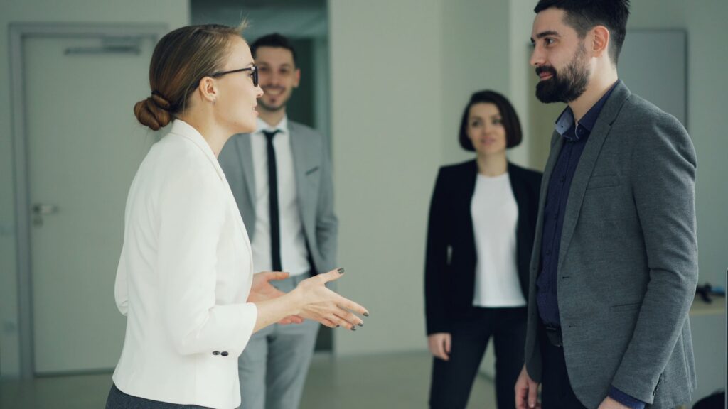 Two business people conversing, others observing.
