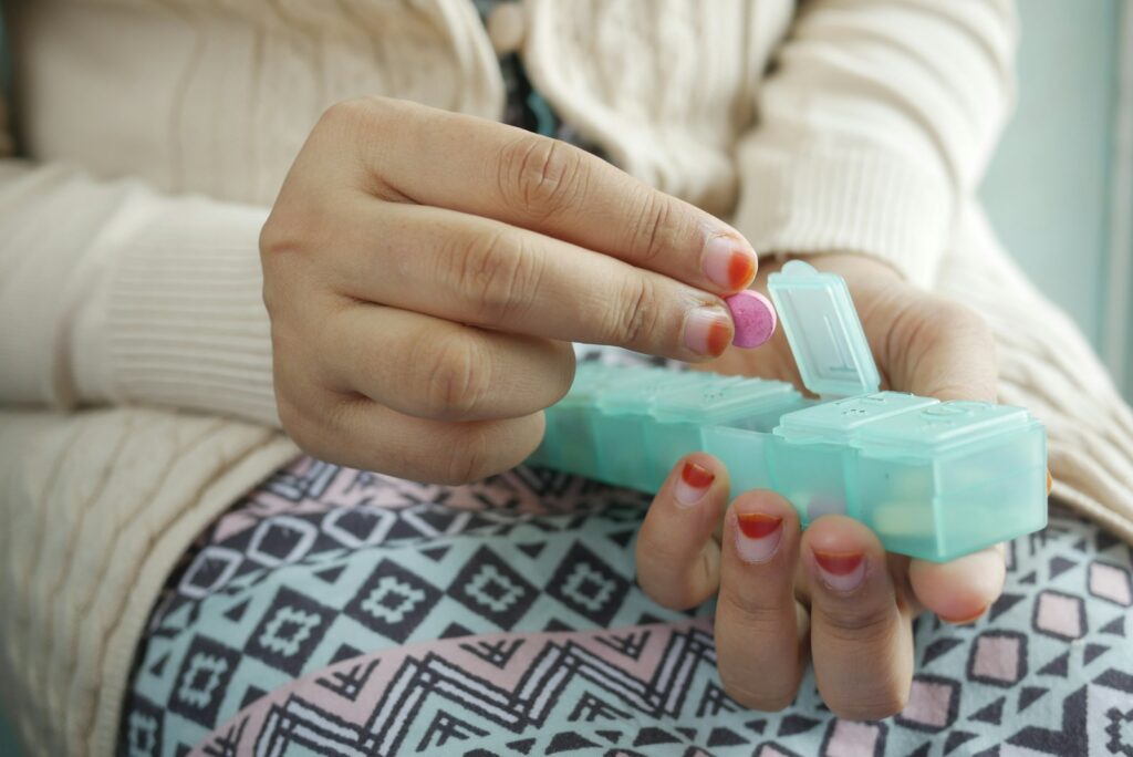 Woman holding white and green plastic container with medication