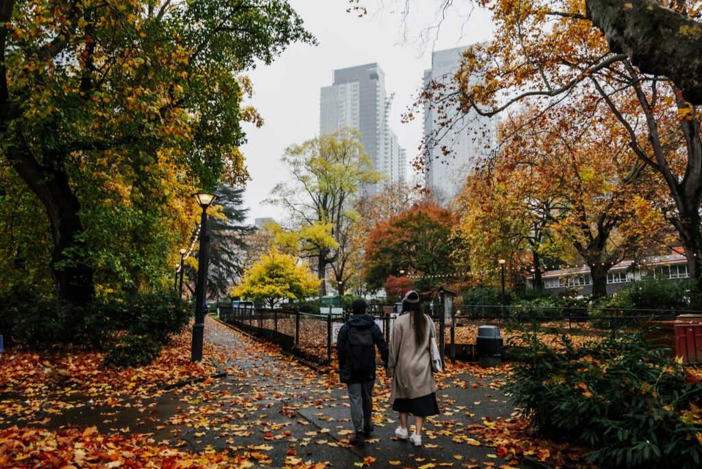 Couple walking on autumn path with city buildings