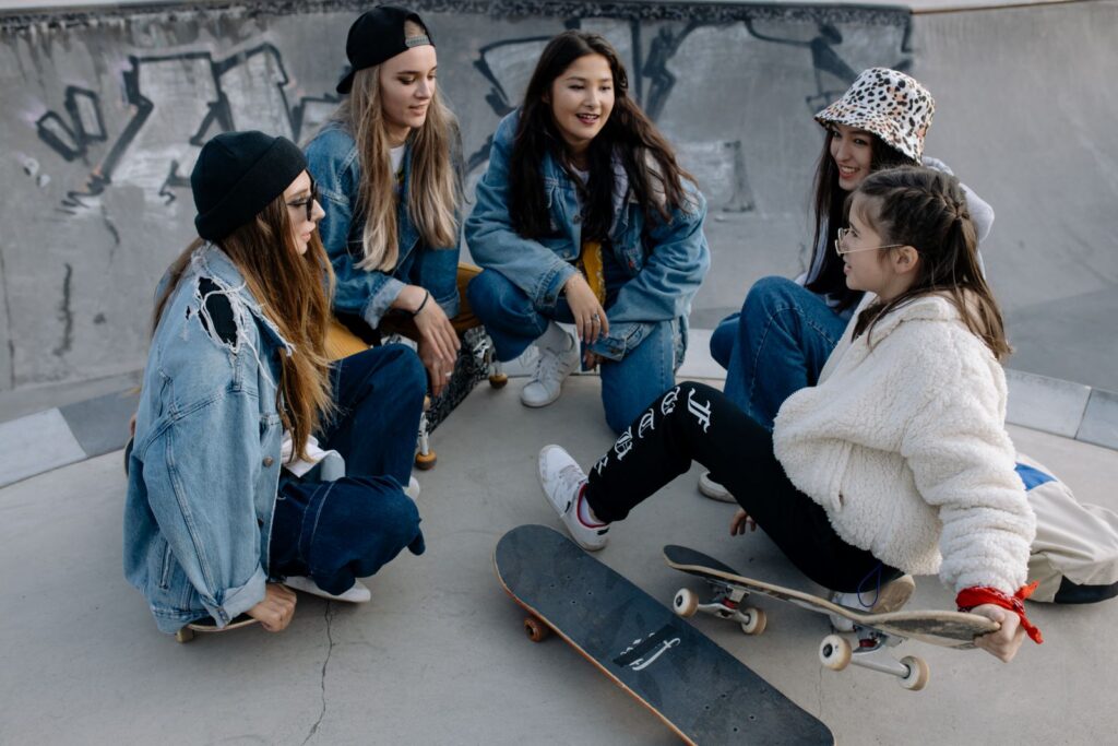 Group of diverse teenagers hanging out at a skatepark, chatting and enjoying leisure time.