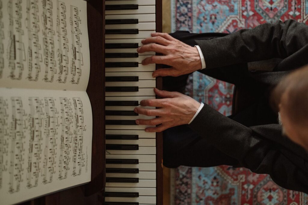 Top view of a pianist playing a piano with an open music sheet, featuring detailed handwork.