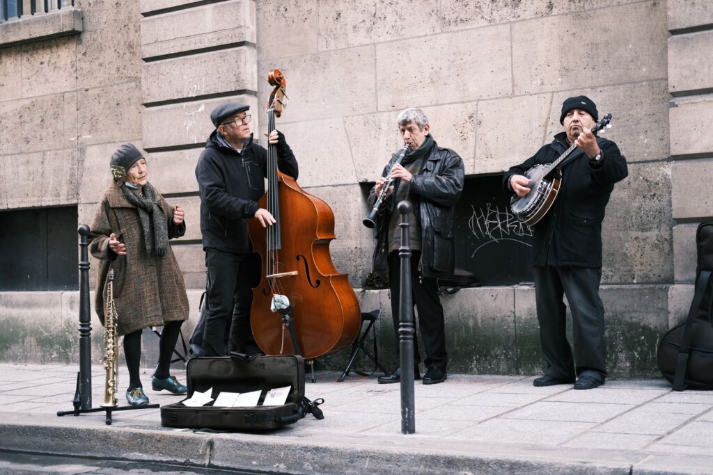 A group of street musicians performing lively music on a Parisian sidewalk.