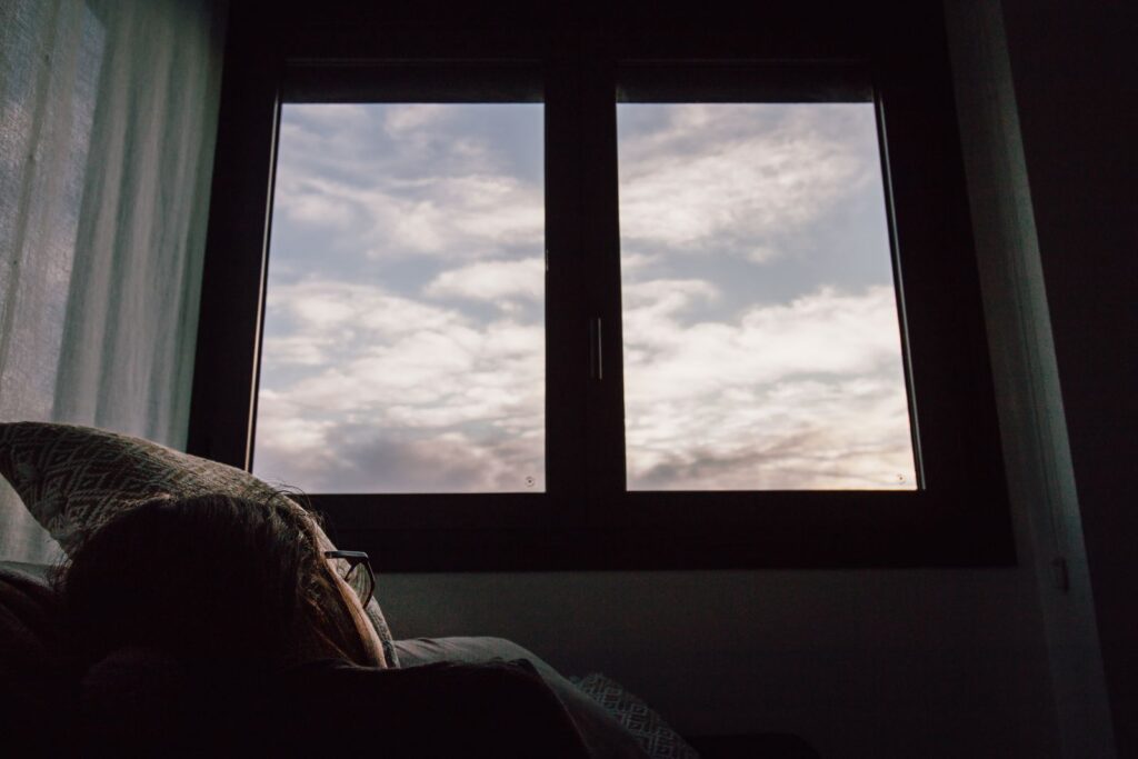 A serene view of the sky with clouds through a window, witnessed from a cozy bedroom setting.