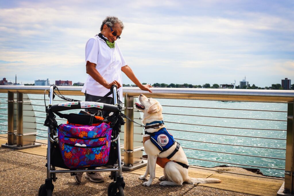 A senior woman enjoying a day by the water with her service dog in Detroit.