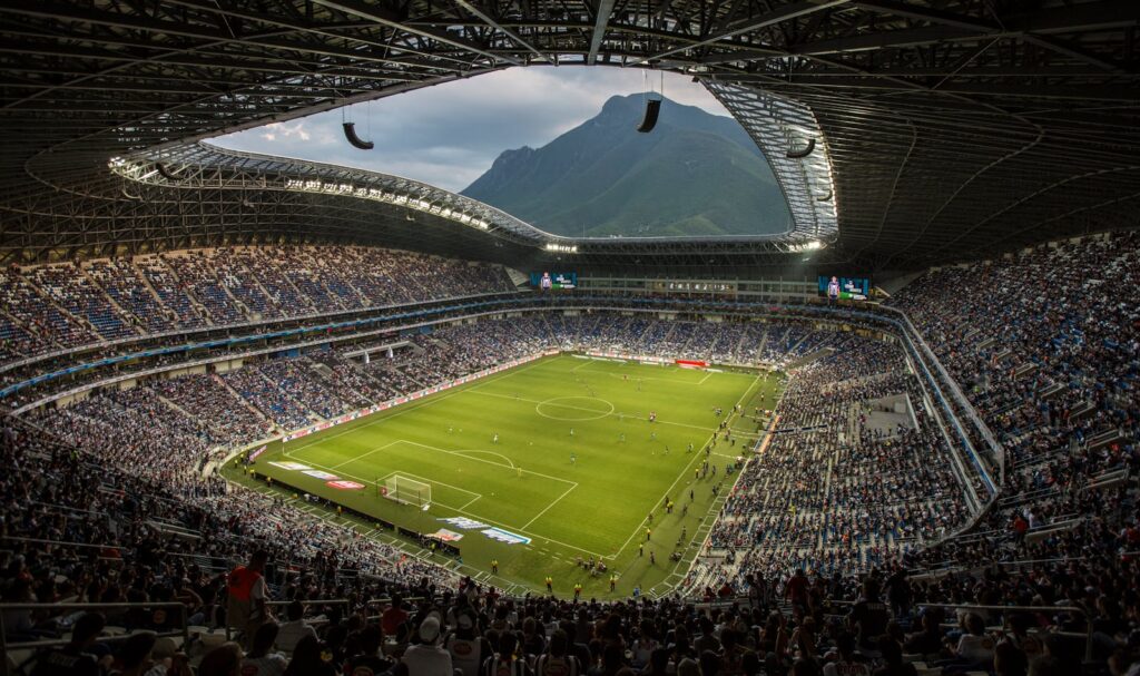 A vibrant football match at Estadio BBVA with a backdrop of Cerro de la Silla, Monterrey.