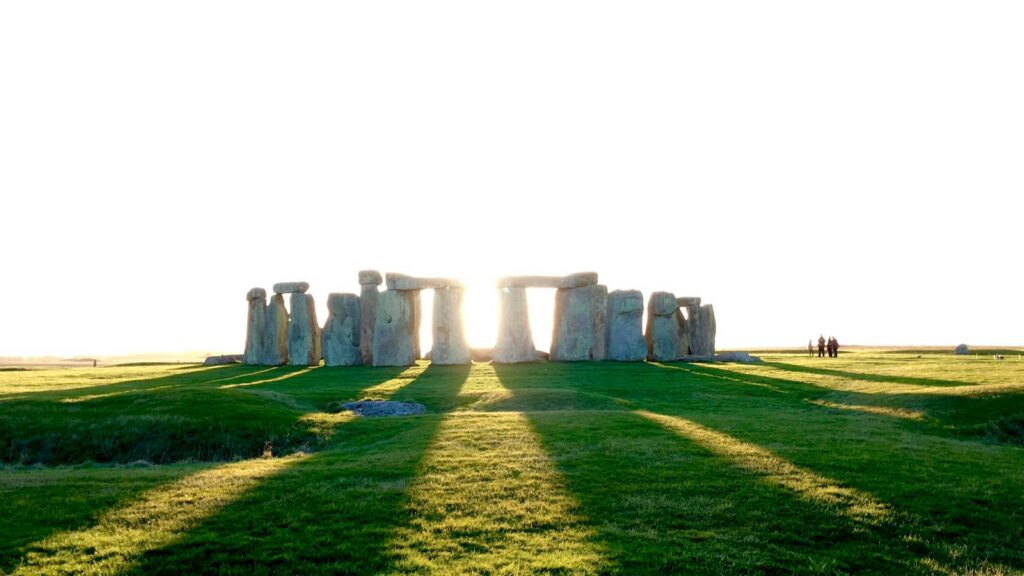 Explore the iconic Stonehenge under the bright sunlight casting long shadows across the grass.