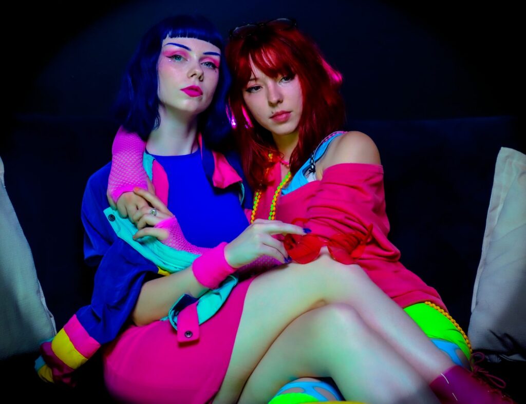 Colorful portrait of two women in neon attire, embracing vibrant fashion and style.