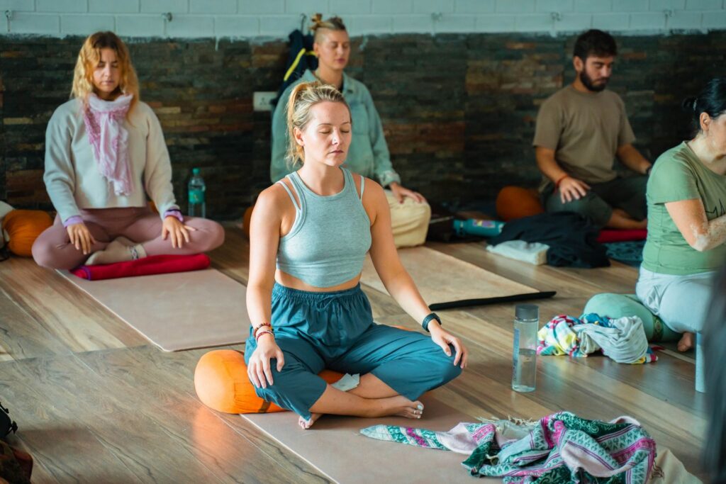 Group practicing meditation and yoga indoors in Rishikesh, India.