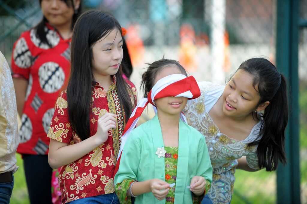 Group of children enjoying a blindfold game in a garden setting, filled with fun and laughter.