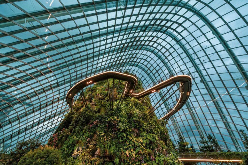 Stunning interior of a glass-domed tropical garden showcasing lush flora and modern architecture.