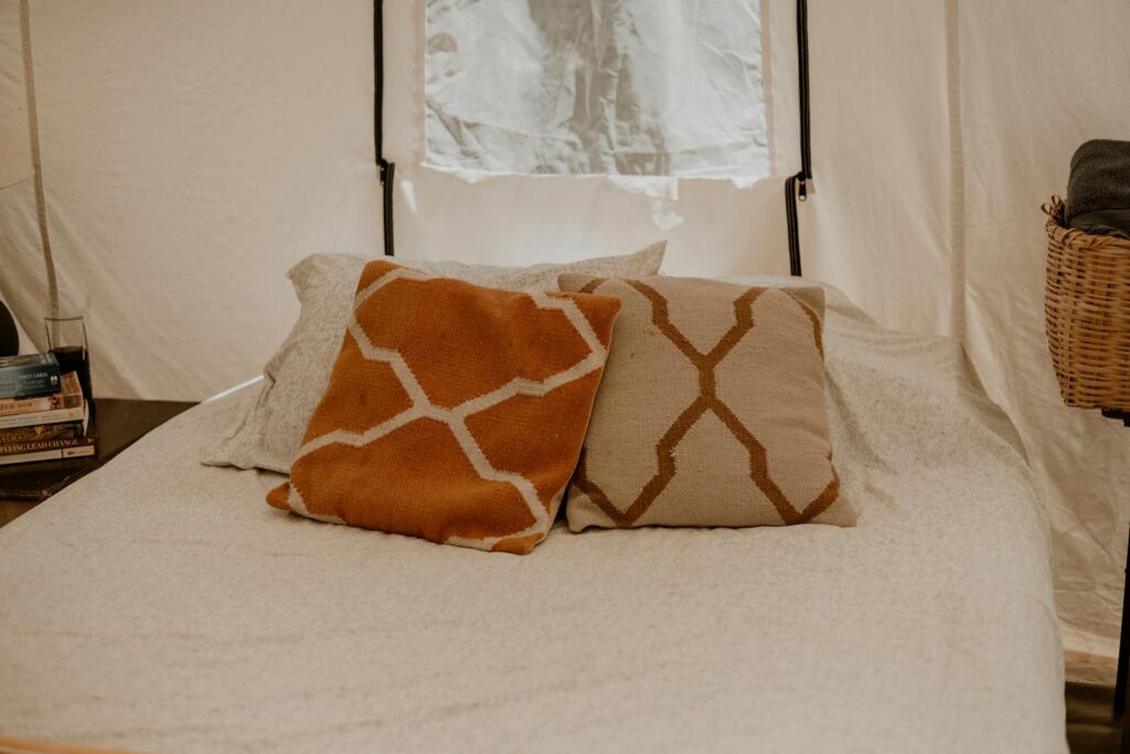 Comfortable bed setup with patterned cushions and soft lighting inside a camping tent.