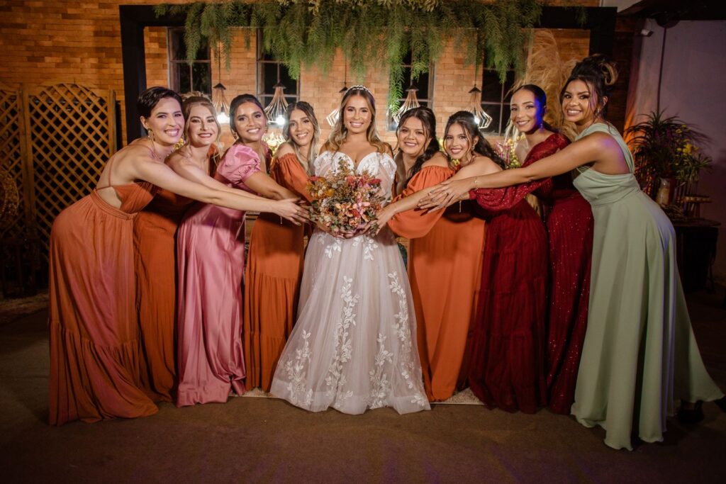 A cheerful bride and bridesmaids celebrate together with vibrant dresses indoors.