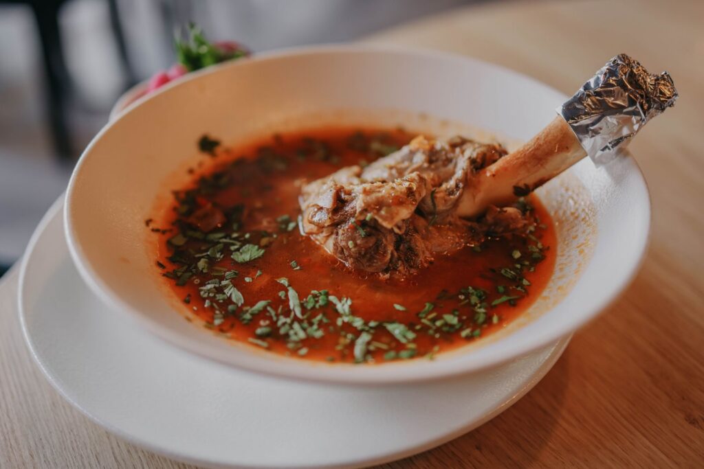 Delicious lamb shank soup garnished with fresh herbs, perfect for a cozy meal.