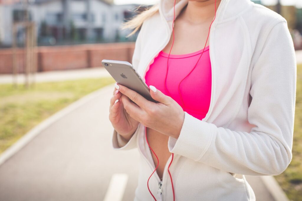 Young woman outdoors using smartphone and earphones for workout music.