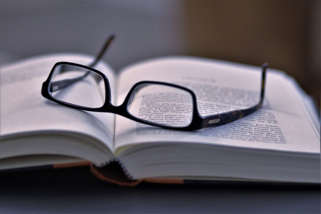 Close-up of eyeglasses resting on an open book, highlighting reading and literature.