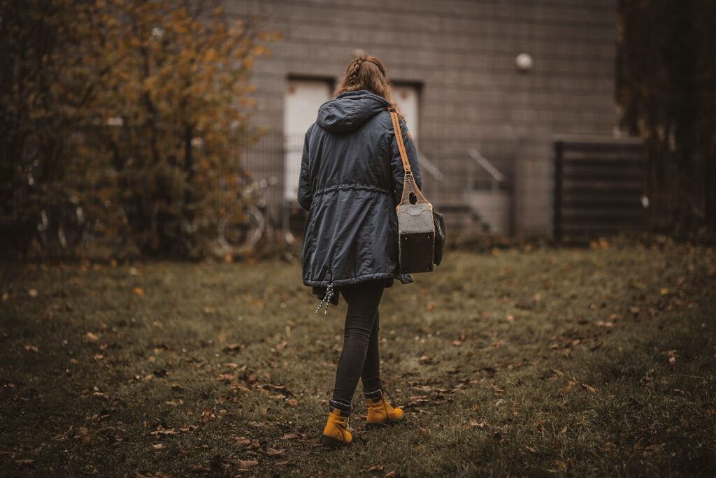 a woman standing in a yard with a handbag