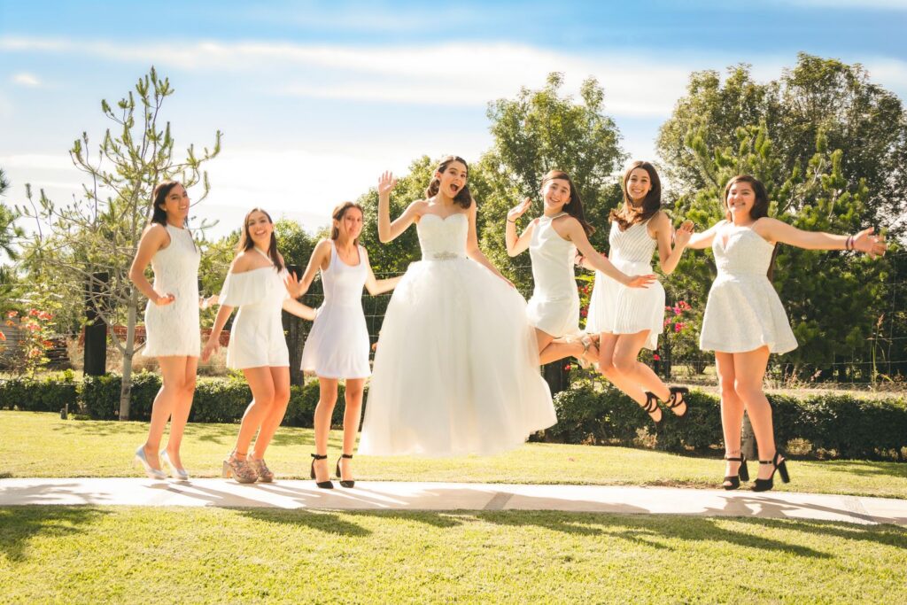 A happy group of bridesmaids and a bride joyfully jumping outdoors in León, México.