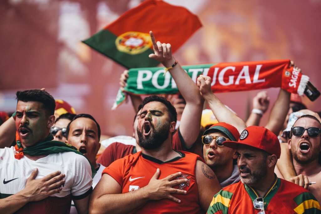 Passionate Portugal football supporters cheering with flags and scarves in vibrant celebration.