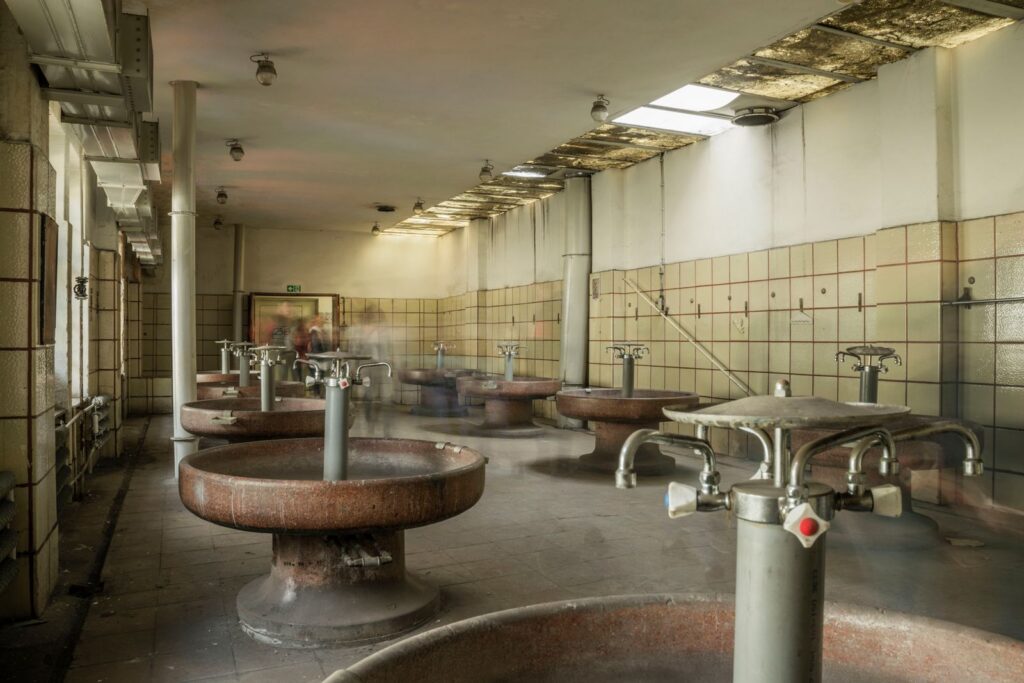 Vintage bathhouse interior in Wrocław, Poland, showcasing old faucets and tiled walls.