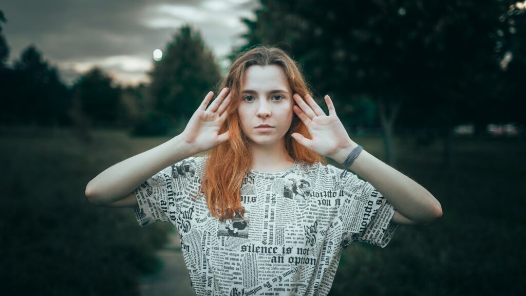 Young woman with hands raised in park