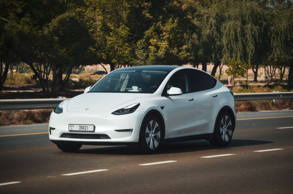 A sleek white Tesla car cruising on a sunny highway in Abu Dhabi, UAE.