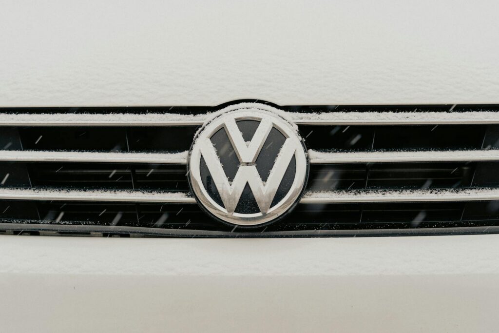 Closeup of a snow-dusted Volkswagen car grille shows the iconic VW logo.