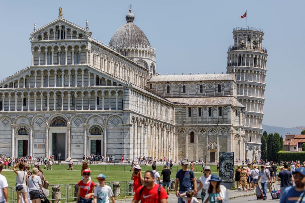 Crowds explore the Pisa Cathedral and iconic Leaning Tower on a sunny day in Pisa, Italy.