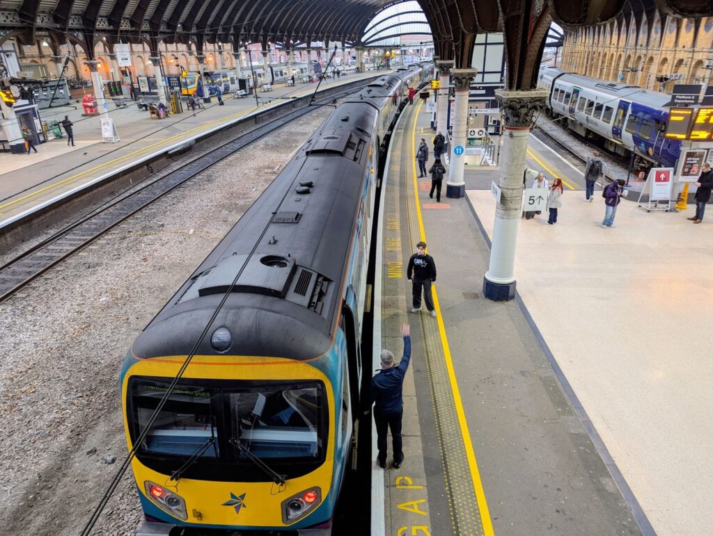 Overhead view of York train station with people on the platform and trains ready for departure.