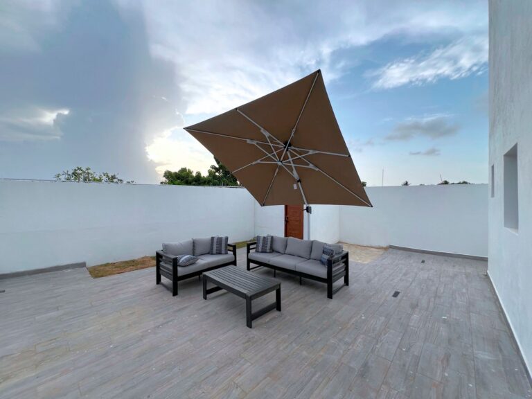Contemporary outdoor patio featuring a sofa set and cantilever umbrella under a cloudy sky.