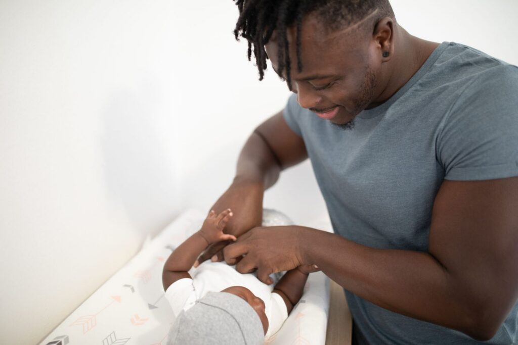 Loving father joyfully interacts with baby during diaper change.