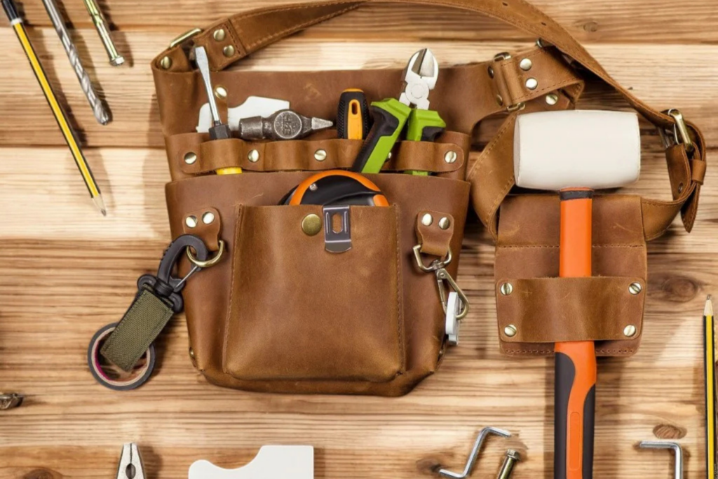 High-quality leather tool belt with essential carpenter tools on a wooden table.