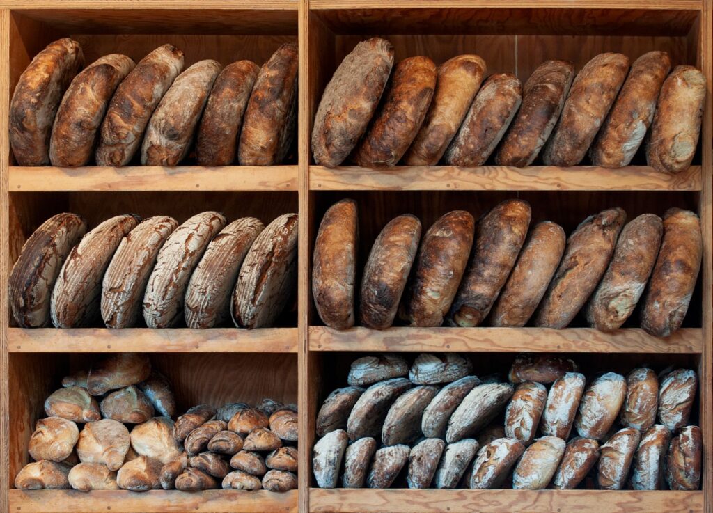 A variety of artisanal breads neatly arranged on wooden shelves, creating a rustic display.