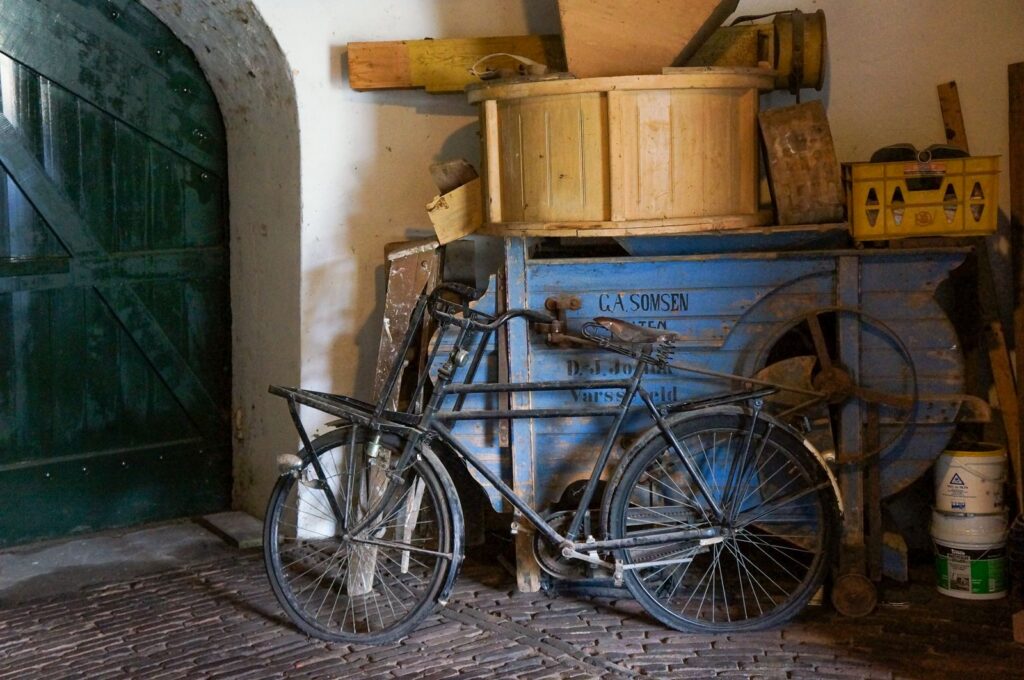 An old bicycle rests in a rustic, cluttered warehouse interior, capturing a vintage and industrial atmosphere.
