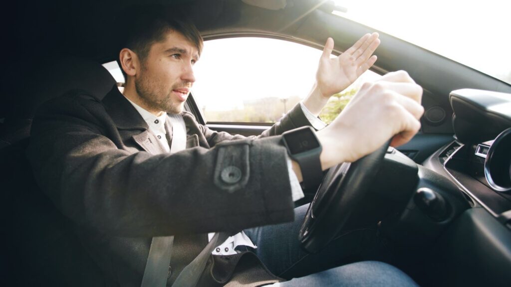 Man showing frustration while driving a car, highlighting road rage issues.