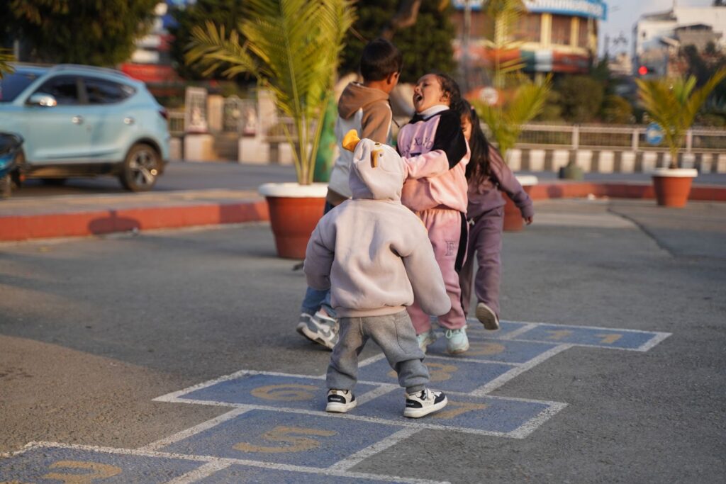 Joyful children playing hopscotch outdoors in Kathmandu, Nepal.