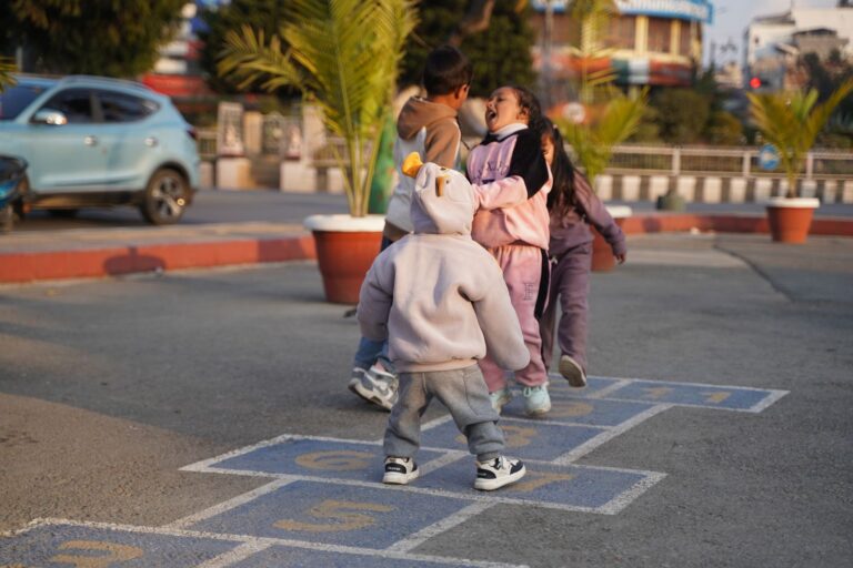 Joyful children playing hopscotch outdoors in Kathmandu, Nepal.