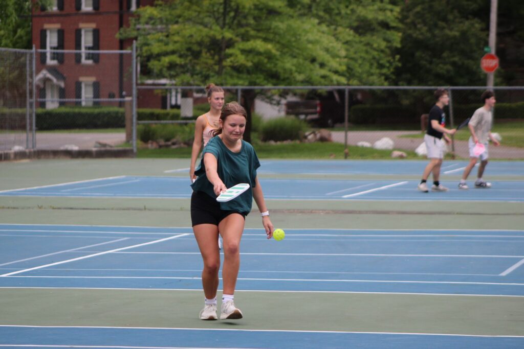 Group of young adults playing pickleball on an outdoor court in Ohio, capturing the spirit of fun and athleticism.