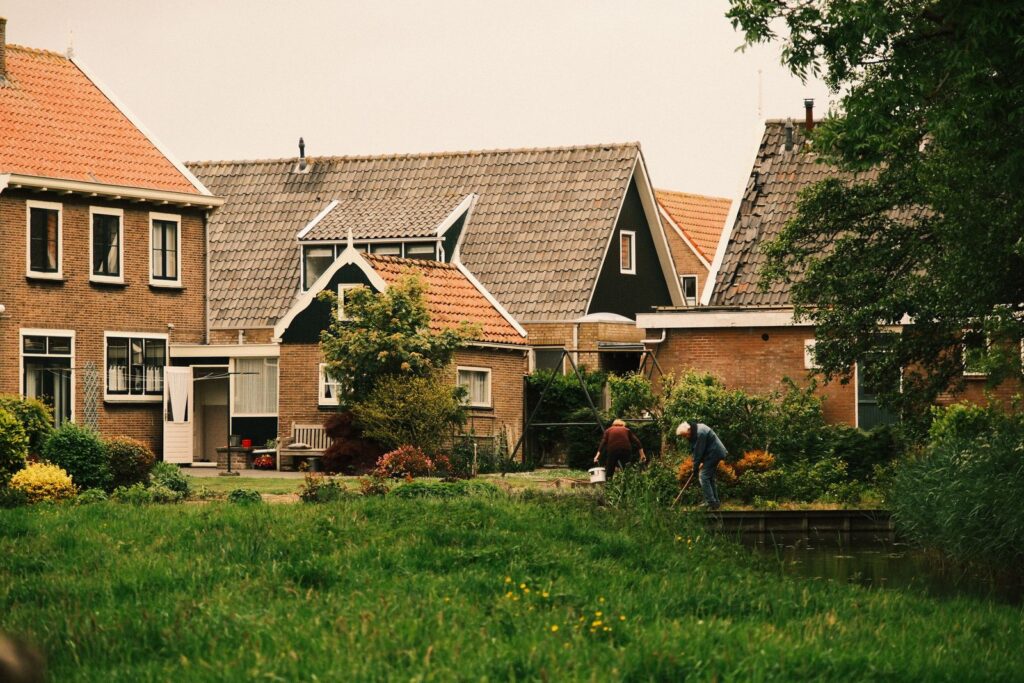 Picturesque view of Dutch suburban homes with lush gardens and people gardening.