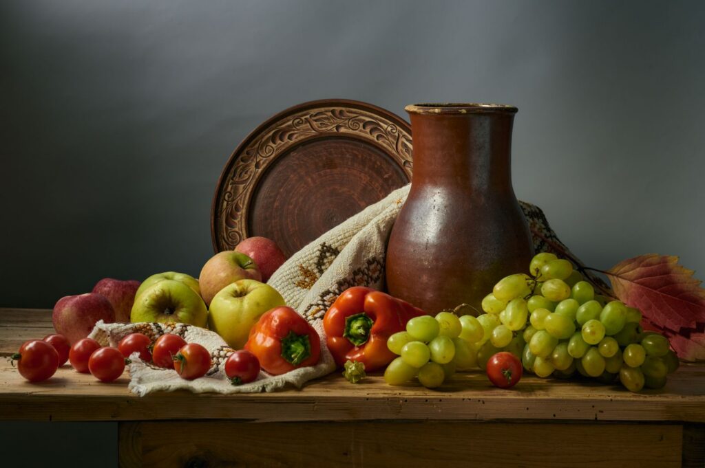 Ancient Greek-style harvest table with fruit, grapes, and clay pottery