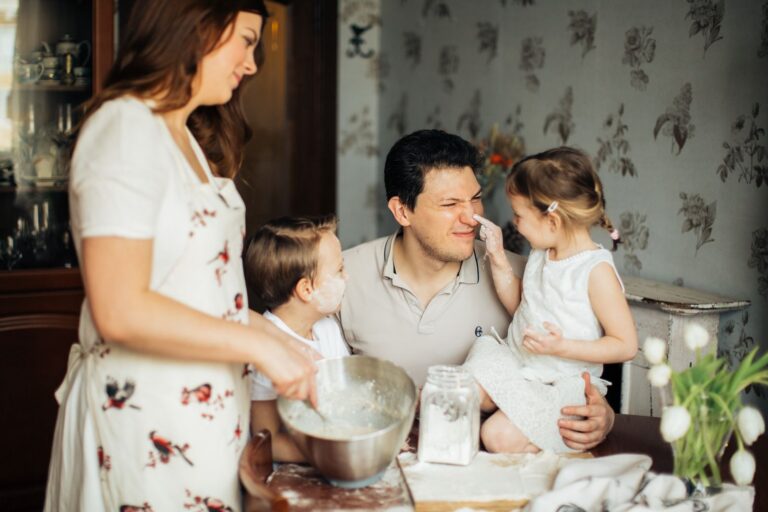 A joyful family moment with parents and children baking together in the kitchen.