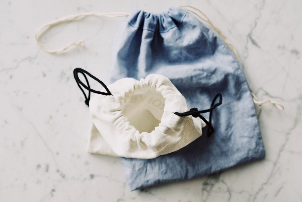 Top view of composed blue and white modern plain fabric bags on marble table in room