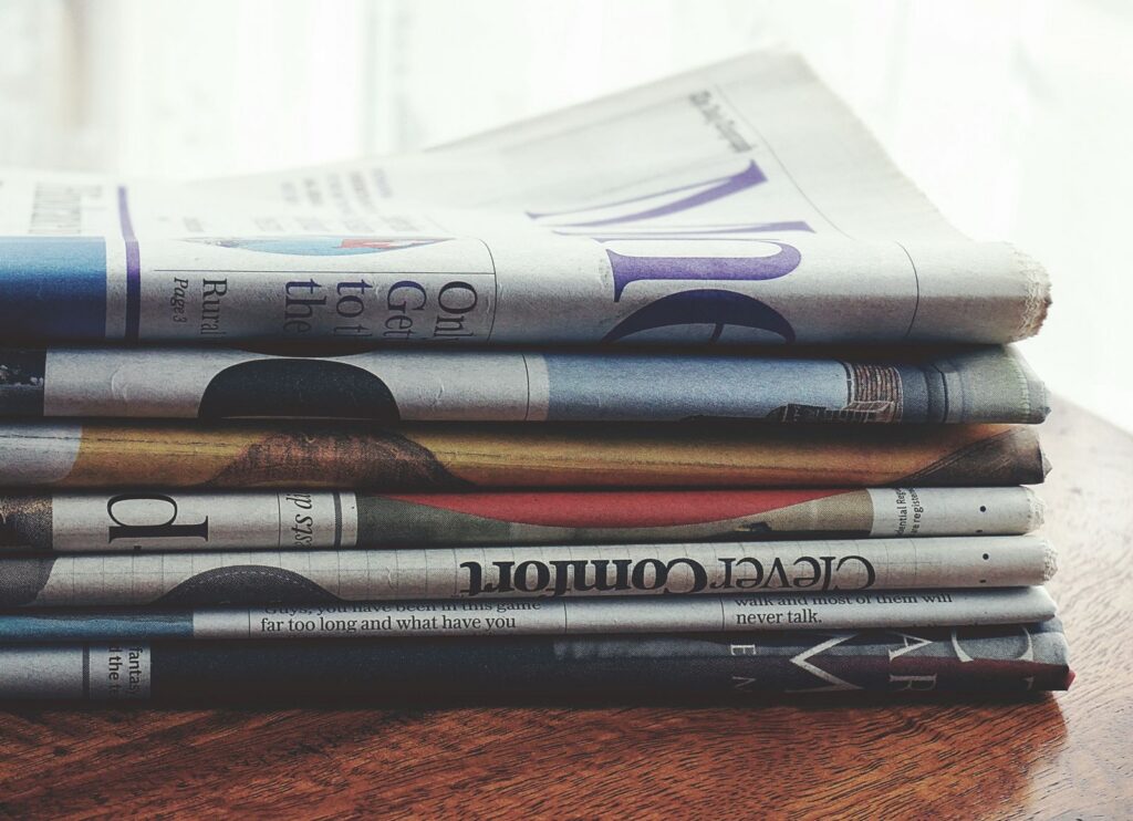 A stack of folded newspapers placed on a wooden table, symbolizing news and information.